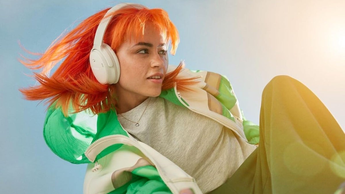 A woman wearing a set of Bose QuietComfort headphones.